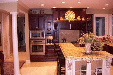 Inspiration for a mid-sized timeless l-shaped kitchen remodel in Indianapolis with raised-panel cabinets, dark wood cabinets, granite countertops, beige backsplash, stone tile backsplash, stainless steel appliances and an island