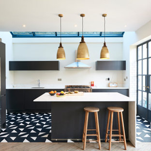 Contemporary l-shaped kitchen in London with a submerged sink, flat-panel cabinets, black cabinets, white splashback, white appliances, an island and multi-coloured floors.