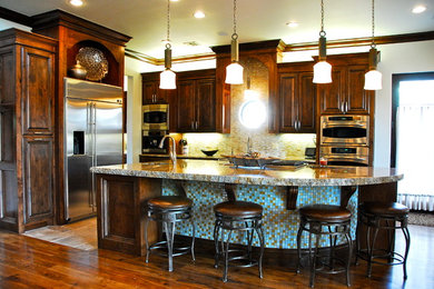 Eat-in kitchen - transitional l-shaped eat-in kitchen idea in Other with an undermount sink, blue cabinets, granite countertops, glass tile backsplash, stainless steel appliances and raised-panel cabinets