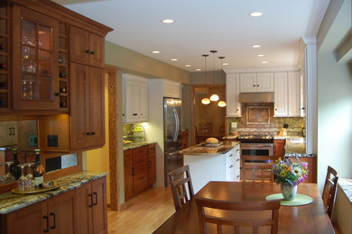Mid-sized elegant u-shaped light wood floor and brown floor eat-in kitchen photo in Chicago with stainless steel appliances, an undermount sink, flat-panel cabinets, granite countertops, porcelain backsplash, an island, white cabinets and multicolored backsplash