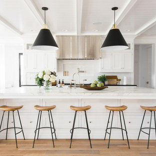 Design ideas for a large beach style kitchen in Salt Lake City with white cabinets, with island, white splashback, shaker cabinets, marble benchtops, light hardwood floors and beige floor.