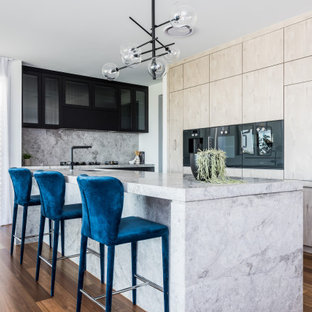 This is an example of an expansive contemporary kitchen in Brisbane with an undermount sink, flat-panel cabinets, limestone benchtops, limestone splashback, black appliances and with island.