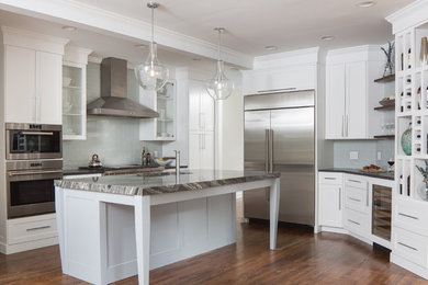 Example of a transitional medium tone wood floor and brown floor kitchen design in Atlanta with an undermount sink, shaker cabinets, white cabinets, blue backsplash, subway tile backsplash, stainless steel appliances, an island and gray countertops