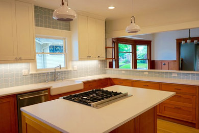 Large arts and crafts u-shaped light wood floor and brown floor enclosed kitchen photo in Portland with a farmhouse sink, shaker cabinets, medium tone wood cabinets, quartz countertops, blue backsplash, ceramic backsplash, stainless steel appliances, an island and white countertops