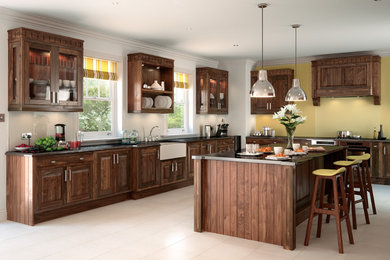 Photo of a l-shaped kitchen in Other with a belfast sink, raised-panel cabinets, glass sheet splashback and an island.