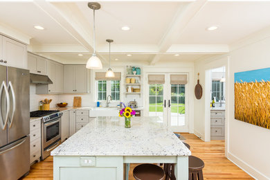 Mid-sized cottage l-shaped light wood floor enclosed kitchen photo in Detroit with a farmhouse sink, shaker cabinets, beige cabinets, quartz countertops, white backsplash, subway tile backsplash, stainless steel appliances and an island