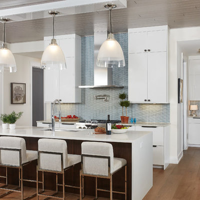 Inspiration for a large contemporary l-shaped medium tone wood floor and brown floor open concept kitchen remodel in Grand Rapids with an undermount sink, flat-panel cabinets, white cabinets, solid surface countertops, blue backsplash, an island, paneled appliances, ceramic backsplash and white countertops
