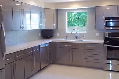 Example of a mid-sized trendy l-shaped ceramic tile kitchen design in Boston with an undermount sink, flat-panel cabinets, stainless steel cabinets, quartz countertops, glass tile backsplash and a peninsula