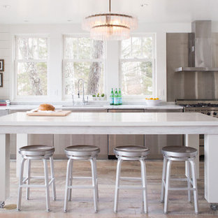 Immagine di una cucina chic di medie dimensioni con ante lisce, ante in acciaio inossidabile, top in marmo, elettrodomestici in acciaio inossidabile, isola, lavello sottopiano, paraspruzzi a effetto metallico e pavimento in legno massello medio