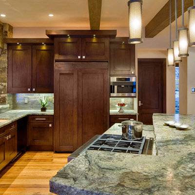 Kitchen - rustic u-shaped medium tone wood floor kitchen idea in Denver with recessed-panel cabinets, dark wood cabinets, stainless steel appliances, an island, an undermount sink, granite countertops, gray backsplash and stone tile backsplash