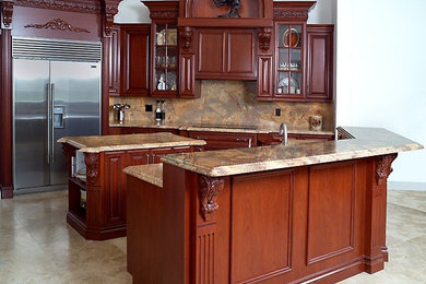 Example of a mid-sized classic l-shaped travertine floor eat-in kitchen design in Miami with recessed-panel cabinets, dark wood cabinets, granite countertops, beige backsplash, stone slab backsplash, stainless steel appliances and two islands