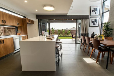 Photo of a medium sized modern single-wall kitchen/diner in Brisbane with a submerged sink, flat-panel cabinets, medium wood cabinets, granite worktops, window splashback, stainless steel appliances, cement flooring and an island.