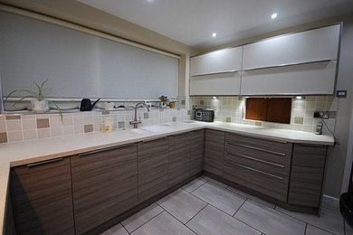 Photo of a contemporary kitchen/diner in Other with an integrated sink, flat-panel cabinets, white cabinets, wood worktops, beige splashback, ceramic splashback, stainless steel appliances and a breakfast bar.