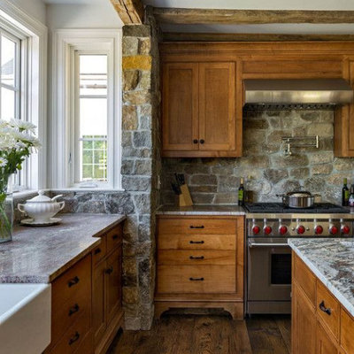 Example of a mid-sized mountain style l-shaped dark wood floor and brown floor eat-in kitchen design in Columbus with a farmhouse sink, flat-panel cabinets, light wood cabinets, granite countertops, gray backsplash, stone tile backsplash, stainless steel appliances, an island and gray countertops