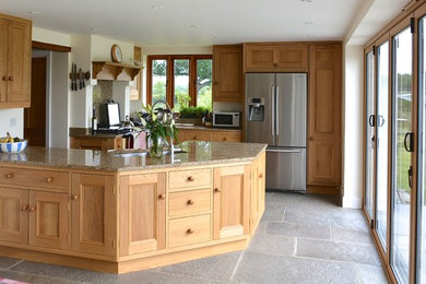 This is an example of a large traditional u-shaped kitchen/diner in Dorset with a double-bowl sink, recessed-panel cabinets, medium wood cabinets, granite worktops, stainless steel appliances, slate flooring and a breakfast bar.