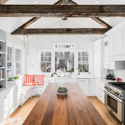 Example of a mid-sized cottage l-shaped light wood floor eat-in kitchen design in New York with an undermount sink, white cabinets, quartz countertops, stainless steel appliances, an island, gray backsplash and shaker cabinets