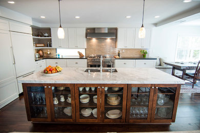 Example of a large transitional l-shaped medium tone wood floor eat-in kitchen design in Los Angeles with a single-bowl sink, recessed-panel cabinets, white cabinets, marble countertops, beige backsplash, subway tile backsplash, stainless steel appliances and an island