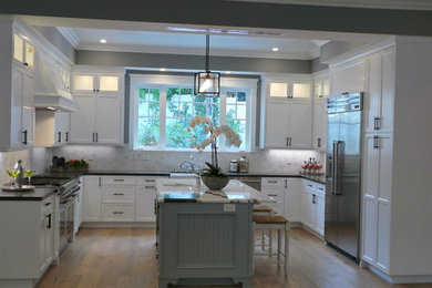 Example of a large arts and crafts u-shaped light wood floor eat-in kitchen design in Los Angeles with a farmhouse sink, shaker cabinets, white cabinets, quartz countertops, white backsplash, mosaic tile backsplash, stainless steel appliances and an island