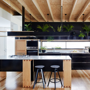 Immagine di una piccola cucina ad ambiente unico contemporanea con ante nere, top in marmo, paraspruzzi bianco, paraspruzzi con piastrelle diamantate, elettrodomestici in acciaio inossidabile, parquet chiaro e isola