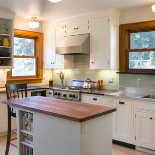 Inspiration for a mid-sized arts and crafts kitchen in Chicago with an integrated sink, shaker cabinets, white cabinets, zinc benchtops, green splashback, subway tile splashback, stainless steel appliances, light hardwood floors, with island and beige floor.