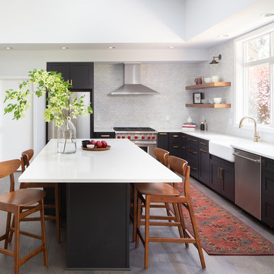 Inspiration for a transitional l-shaped medium tone wood floor and brown floor kitchen remodel in Seattle with a farmhouse sink, shaker cabinets, black cabinets, white backsplash, marble backsplash, stainless steel appliances, an island and white countertops