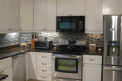 Klassisk inredning av ett avskilt, mellanstort kök, med en undermonterad diskho, skåp i shakerstil, vita skåp, granitbänkskiva, grått stänkskydd, stänkskydd i stickkakel och rostfria vitvaror