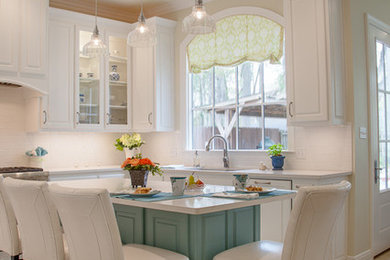 Photo of a large classic u-shaped kitchen/diner in New Orleans with a submerged sink, raised-panel cabinets, white cabinets, engineered stone countertops, white splashback, metro tiled splashback, stainless steel appliances, porcelain flooring and an island.