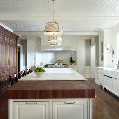Example of a classic kitchen design in Minneapolis with a farmhouse sink, raised-panel cabinets, white cabinets, marble countertops, white backsplash, stone slab backsplash and paneled appliances
