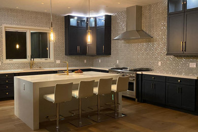 Example of a large transitional u-shaped light wood floor and beige floor eat-in kitchen design in Los Angeles with a drop-in sink, shaker cabinets, blue cabinets, quartz countertops, blue backsplash, ceramic backsplash, stainless steel appliances, an island and white countertops