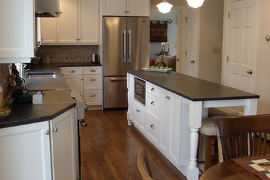 Example of a mid-sized classic l-shaped medium tone wood floor eat-in kitchen design in Portland Maine with a double-bowl sink, shaker cabinets, white cabinets, granite countertops, multicolored backsplash, ceramic backsplash, stainless steel appliances and an island