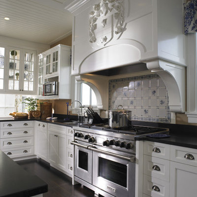 Example of a large classic dark wood floor kitchen design in Boston with recessed-panel cabinets, white cabinets, a farmhouse sink, granite countertops, white backsplash, ceramic backsplash, paneled appliances and an island
