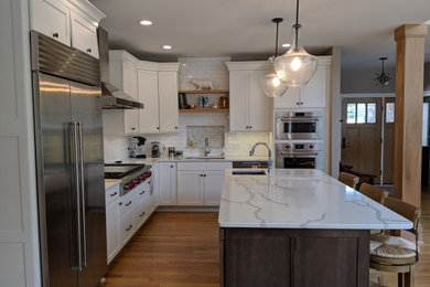 Kitchen - transitional l-shaped medium tone wood floor and multicolored floor kitchen idea in Chicago with an undermount sink, shaker cabinets, white cabinets, white backsplash, subway tile backsplash, stainless steel appliances, an island, white countertops and quartzite countertops