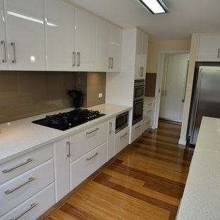This is an example of a large modern l-shaped eat-in kitchen in Melbourne with a double-bowl sink, open cabinets, white cabinets, granite benchtops, brown splashback, glass sheet splashback, stainless steel appliances, bamboo floors and with island.