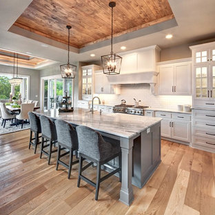 Foto di una cucina abitabile chic con lavello stile country, ante bianche, paraspruzzi bianco, paraspruzzi con piastrelle diamantate, elettrodomestici in acciaio inossidabile, parquet chiaro, isola, pavimento beige, top grigio e ante in stile shaker