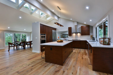 Exempel på ett stort modernt kök, med en enkel diskho, släta luckor, skåp i mörkt trä, bänkskiva i kvarts, vitt stänkskydd, stänkskydd i keramik, rostfria vitvaror, ljust trägolv och en köksö