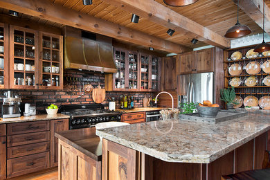 Photo of a large rustic l-shaped kitchen/diner in New York with glass-front cabinets, medium wood cabinets, granite worktops, brown splashback, brick splashback, coloured appliances, medium hardwood flooring, an island and brown floors.
