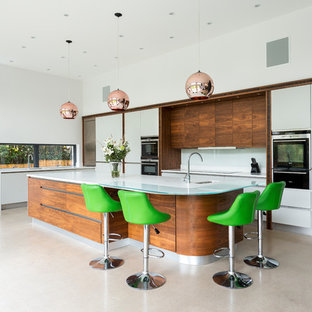 Photo of a medium sized contemporary l-shaped kitchen in Other with a submerged sink, flat-panel cabinets, white cabinets, white splashback, glass sheet splashback, black appliances, an island, beige floors and white worktops.
