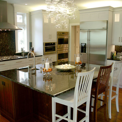 Eat-in kitchen - mid-sized traditional l-shaped medium tone wood floor eat-in kitchen idea in Milwaukee with shaker cabinets, white cabinets, stainless steel appliances, a single-bowl sink, marble countertops, black backsplash, an island and stone slab backsplash