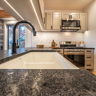 Foto di una cucina minimal di medie dimensioni con lavello stile country, ante in stile shaker, ante grigie, top in granito, paraspruzzi grigio, paraspruzzi in granito, elettrodomestici in acciaio inossidabile, pavimento in legno massello medio, penisola, top grigio e travi a vista