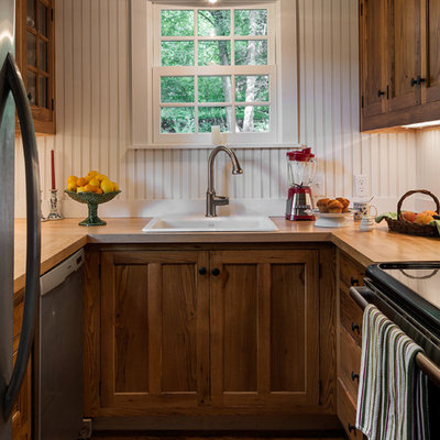 Inspiration for a small timeless u-shaped enclosed kitchen remodel in New York with a drop-in sink, recessed-panel cabinets, dark wood cabinets, wood countertops and stainless steel appliances