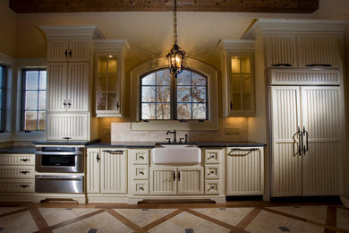 Inspiration for a mediterranean kitchen remodel in Austin with a farmhouse sink, beige cabinets and beige backsplash
