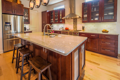 Eat-in kitchen - mid-sized contemporary l-shaped light wood floor and beige floor eat-in kitchen idea in Atlanta with glass-front cabinets, dark wood cabinets, an island, an undermount sink, granite countertops, beige backsplash, ceramic backsplash and stainless steel appliances