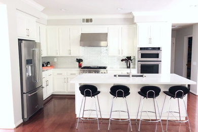 Exempel på ett modernt vit vitt kök, med en undermonterad diskho, luckor med infälld panel, vita skåp, bänkskiva i kvarts, vitt stänkskydd, stänkskydd i glaskakel, rostfria vitvaror, mellanmörkt trägolv och brunt golv