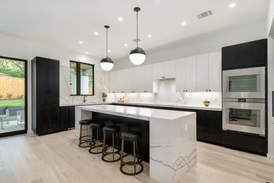 Kitchen - mid-sized contemporary l-shaped light wood floor and beige floor kitchen idea in Austin with flat-panel cabinets, marble countertops, an island, white countertops, white backsplash, marble backsplash, stainless steel appliances and an undermount sink