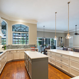 Large transitional open concept kitchen designs - Inspiration for a large transitional u-shaped open concept kitchen remodel in Tampa with recessed-panel cabinets, white cabinets, quartz countertops, metallic backsplash, glass tile backsplash, paneled appliances and an island