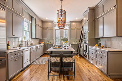 Large transitional u-shaped medium tone wood floor and brown floor enclosed kitchen photo in Nashville with an undermount sink, recessed-panel cabinets, gray cabinets, granite countertops, white backsplash, mosaic tile backsplash, stainless steel appliances, an island and multicolored countertops