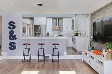 Eat-in kitchen - mid-sized contemporary galley light wood floor eat-in kitchen idea in Orange County with a farmhouse sink, shaker cabinets, white cabinets, quartz countertops, multicolored backsplash, mosaic tile backsplash, stainless steel appliances and a peninsula