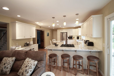 Example of a mid-sized transitional l-shaped light wood floor open concept kitchen design in Philadelphia with shaker cabinets, white cabinets, granite countertops, white backsplash, subway tile backsplash, stainless steel appliances, an island and a double-bowl sink