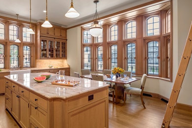 Example of a huge classic medium tone wood floor and brown floor eat-in kitchen design in Bridgeport with a farmhouse sink, glass-front cabinets, medium tone wood cabinets, stainless steel appliances and an island