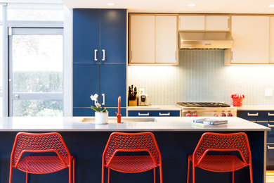 Bild på ett mellanstort funkis kök, med en undermonterad diskho, släta luckor, blå skåp, bänkskiva i kvarts, grönt stänkskydd, stänkskydd i glaskakel, rostfria vitvaror, mellanmörkt trägolv och en köksö